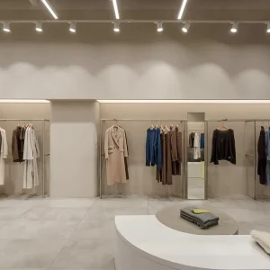 Showcase Stainless Steel Garment Rack Set with Spiral Arc Rail and Full Length Mirror Turnkey Minimalist Fashion Store Fixture